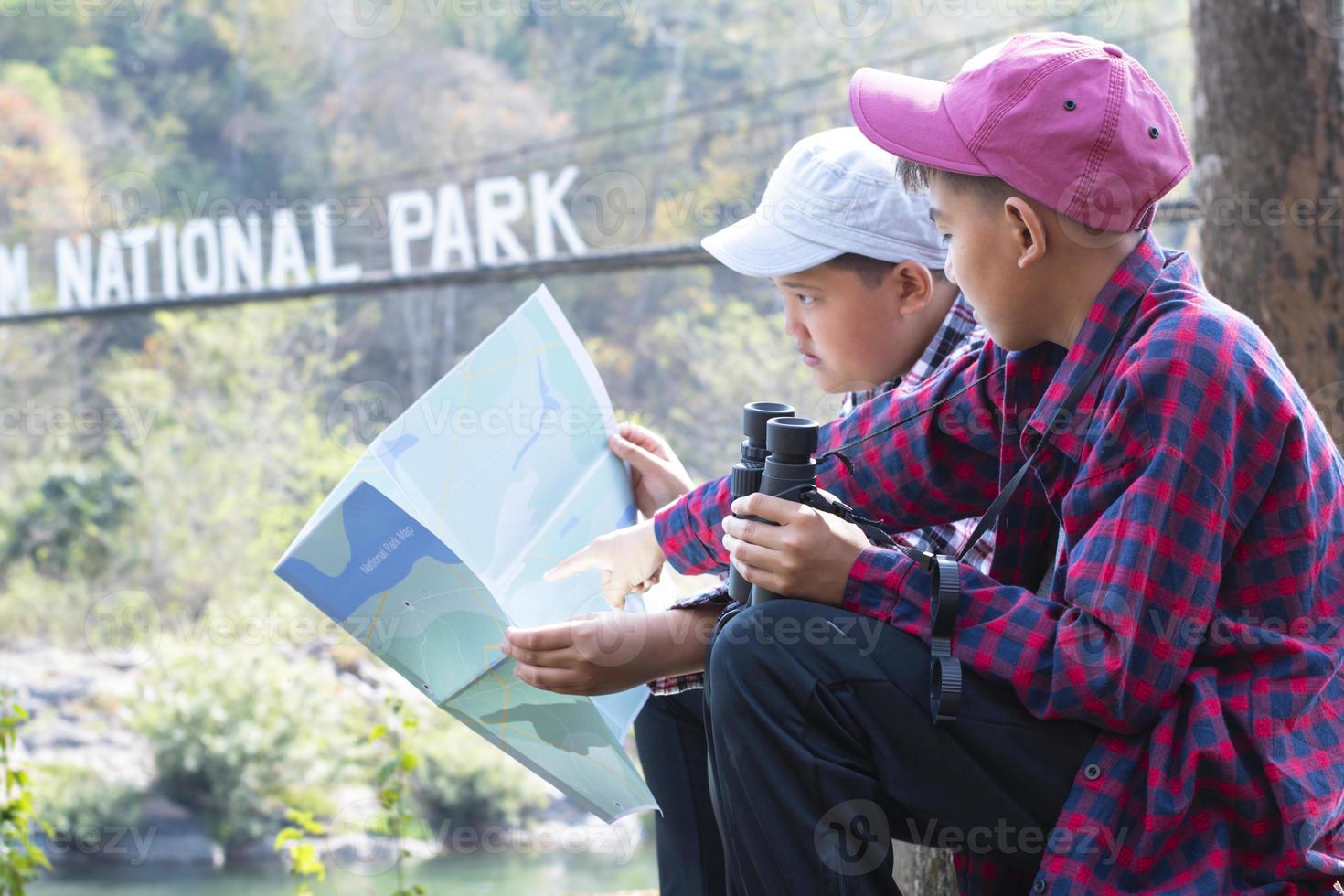 asiático Niños utilizando prismáticos a hacer el ornitología en tropical bosque durante verano acampar, idea para aprendizaje criaturas, fauna silvestre animales y insectos fuera de el aula. foto