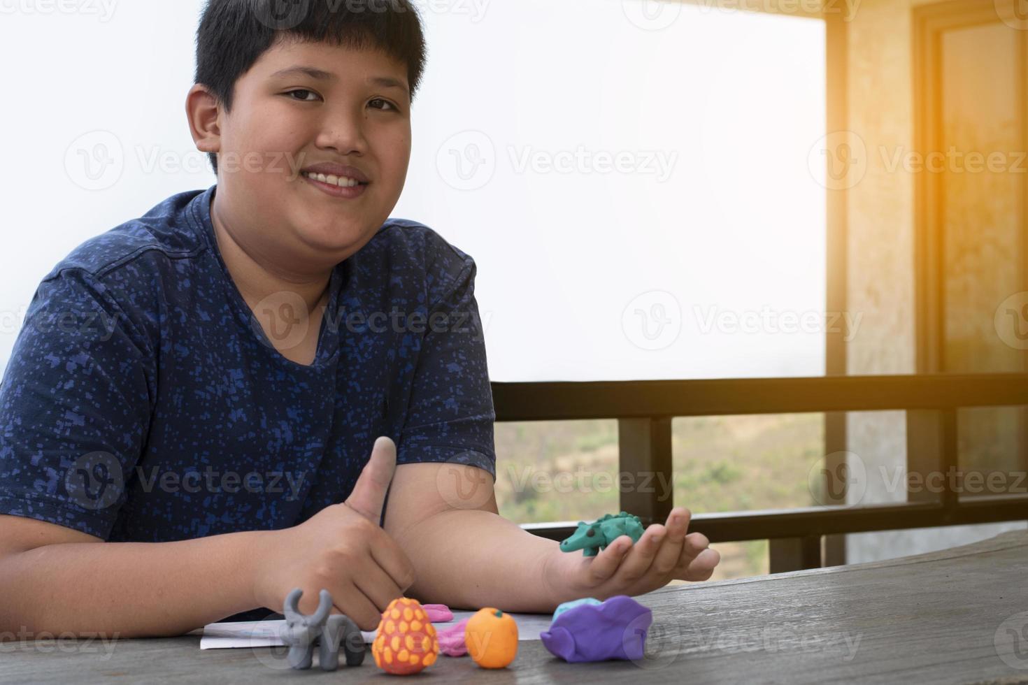 An autistic boy molding different shapes of colored plasticine prepared by parents at home in order to develop various aspects in their son which has slower brain development than normal children. photo