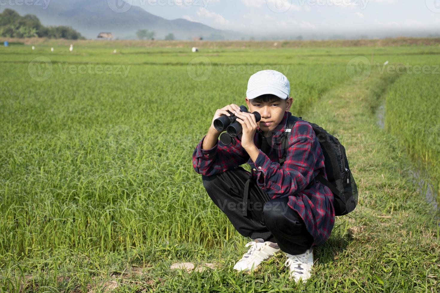 Asian boys using binoculars to do the birdwatching in tropical forest during summer camp, idea for learning creatures, wildlife animals and insects outside the classroom. photo