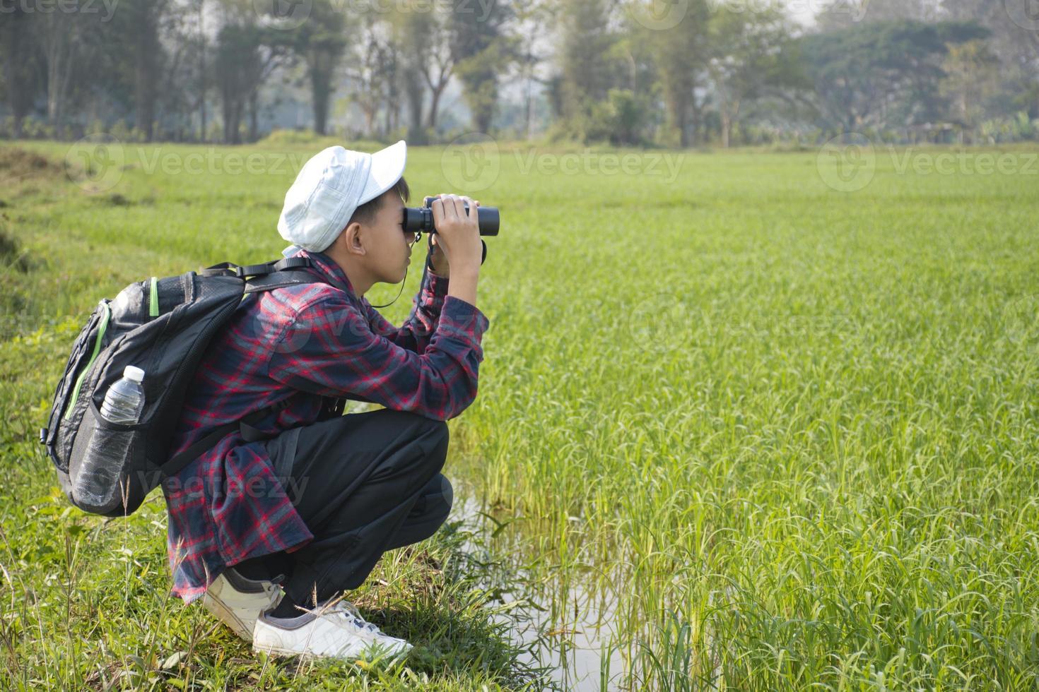 Asian boys using binoculars to do the birdwatching in tropical forest during summer camp, idea for learning creatures, wildlife animals and insects outside the classroom. photo