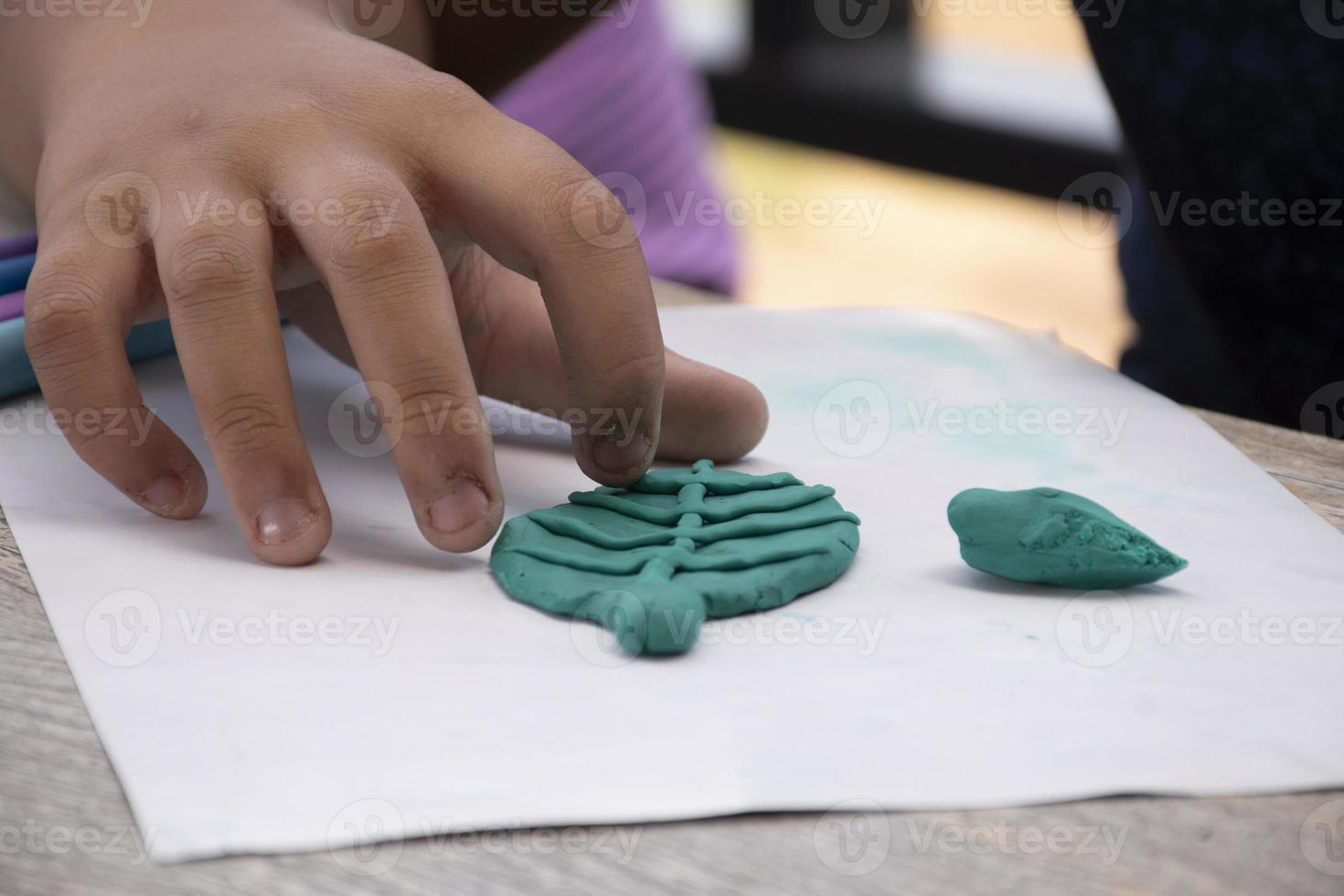 An autistic boy molding different shapes of colored plasticine prepared by parents at home in order to develop various aspects in their son which has slower brain development than normal children. photo