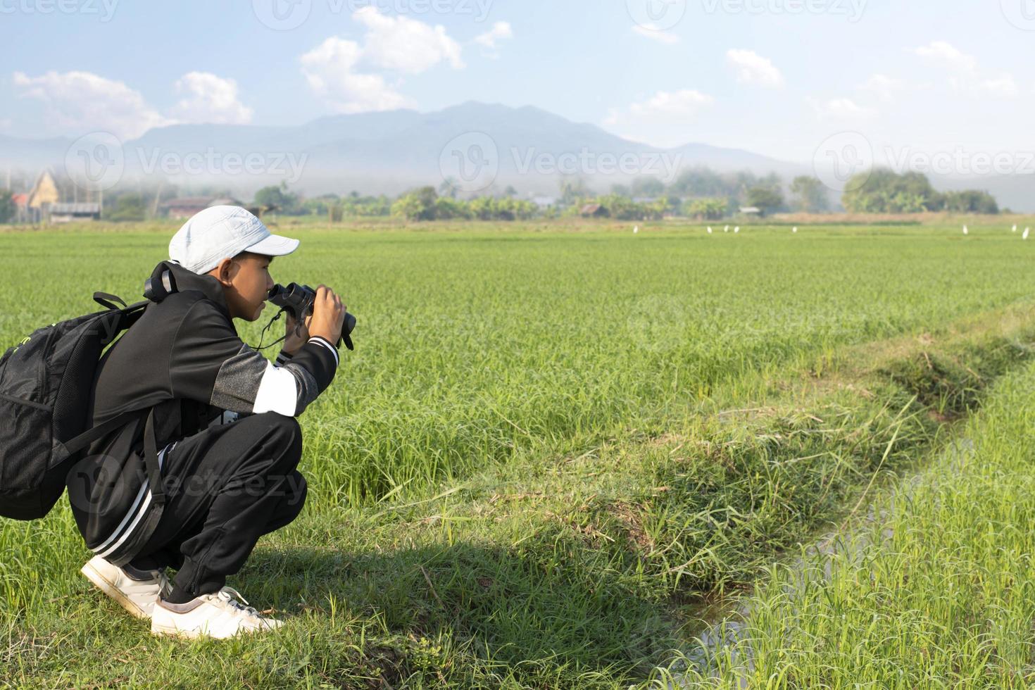 Asian boys using binoculars to do the birdwatching in tropical forest during summer camp, idea for learning creatures, wildlife animals and insects outside the classroom. photo