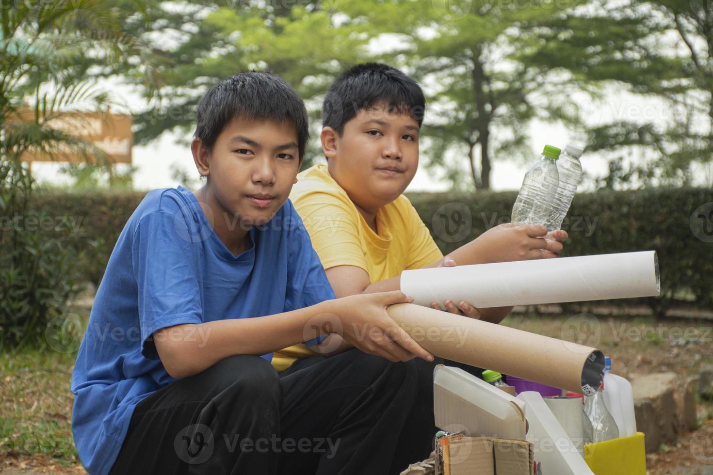 Young asian boy sorting various garbages and putting them into the boxes infront of him in the park, nature care and environment love concept. photo