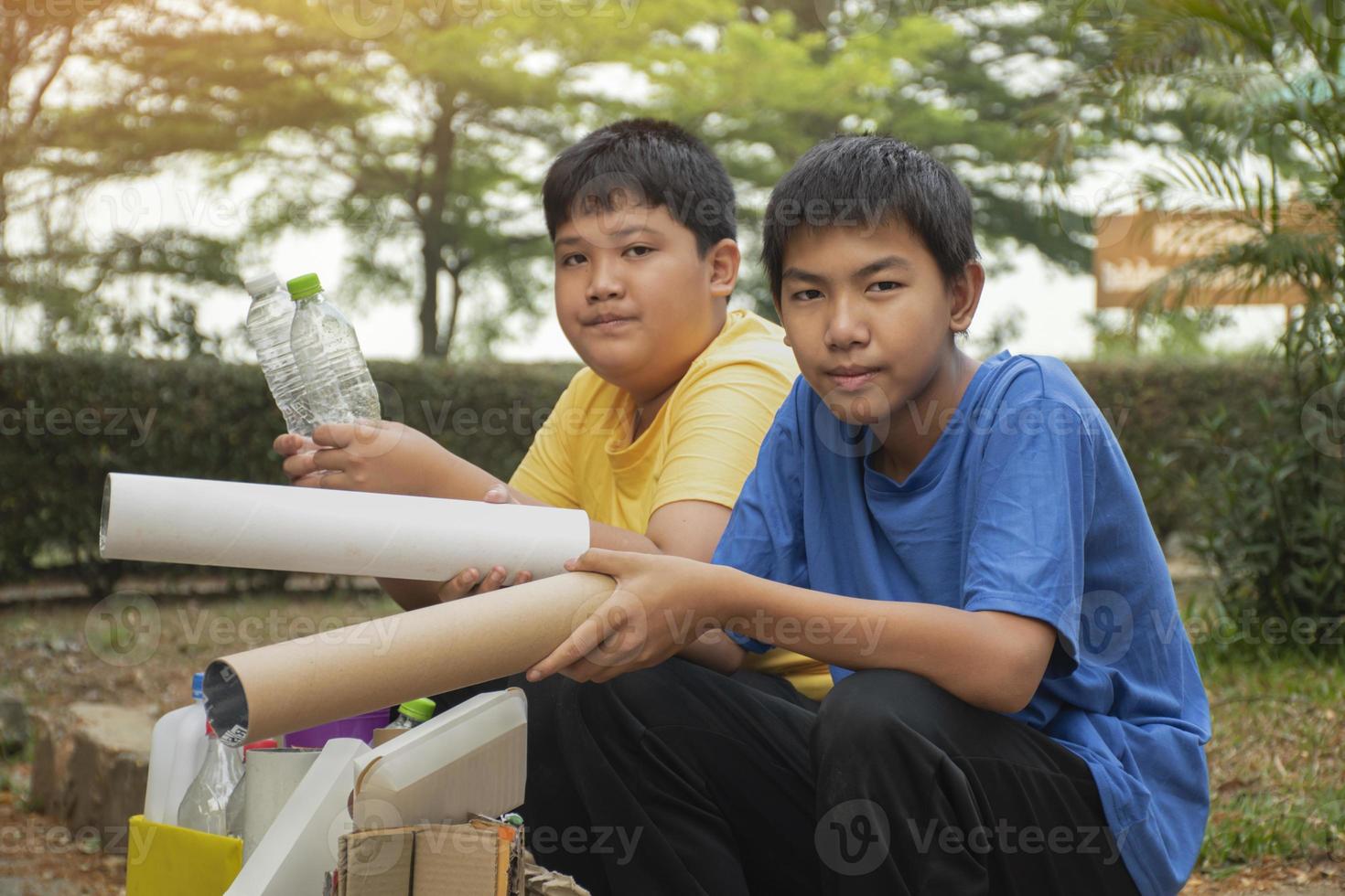 Young asian boy sorting various garbages and putting them into the boxes infront of him in the park, nature care and environment love concept. photo
