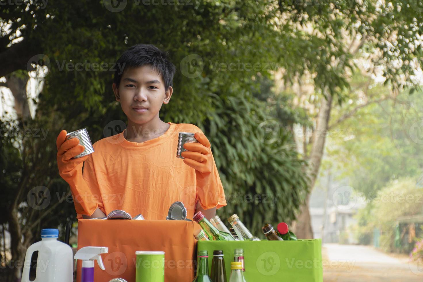 Asian boys are separating garbages and putting them into the boxes in front of them near building, soft and selective focus, environment care, community service and summer vacation activities concept. photo