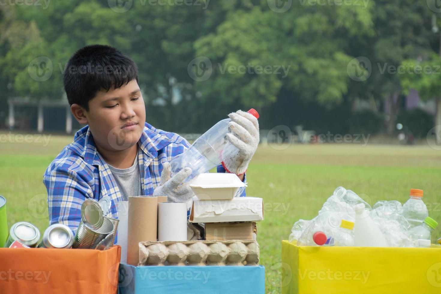 Asian boys are separating garbages and putting them into the boxes in front of them near building, soft and selective focus, environment care, community service and summer vacation activities concept. photo