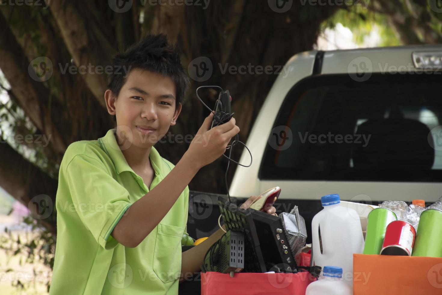 Asian boys are separating garbages and putting them into the boxes in front of them near building, soft and selective focus, environment care, community service and summer vacation activities concept. photo
