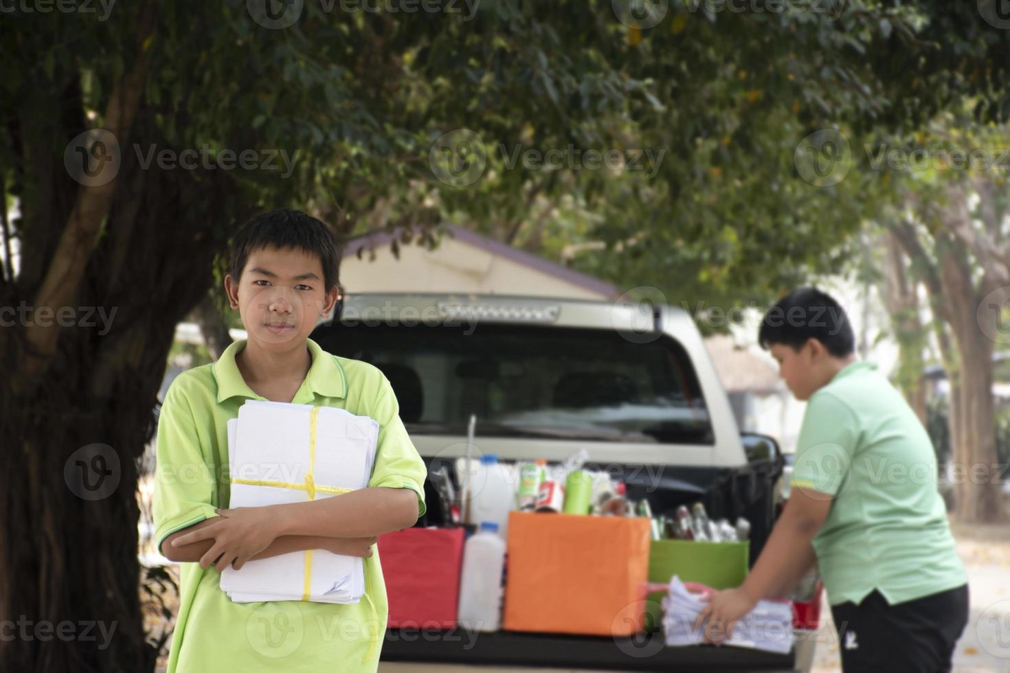 Young asian boy sorting various garbages and putting them into the boxes infront of him in the park, nature care and environment love concept. photo