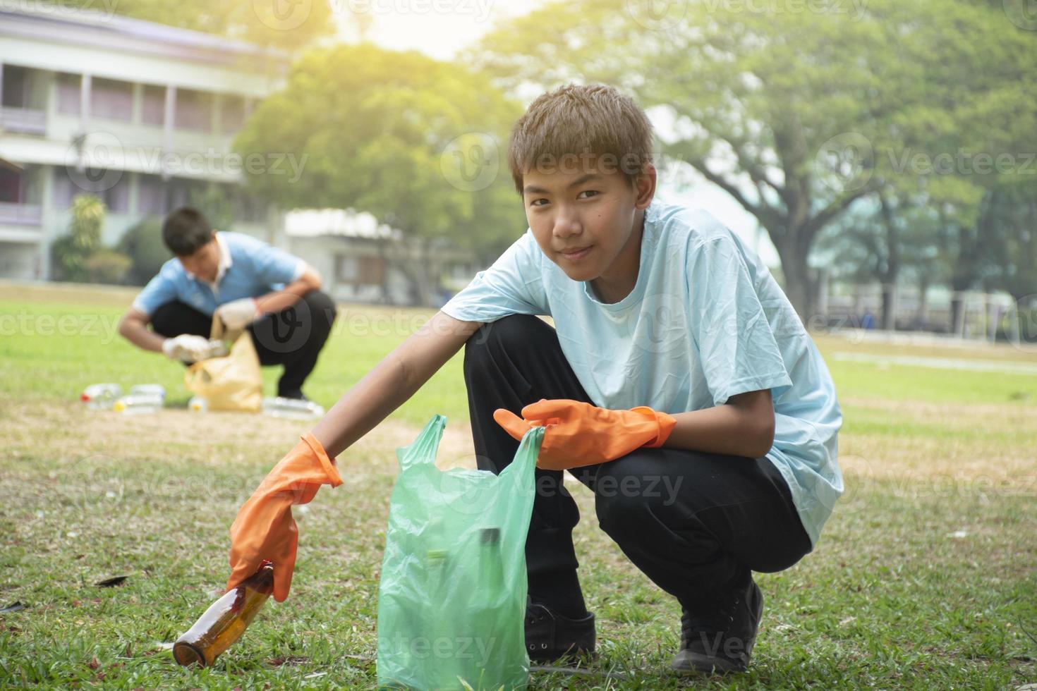 Young asian boy sorting various garbages and putting them into the boxes infront of him in the park, nature care and environment love concept. photo