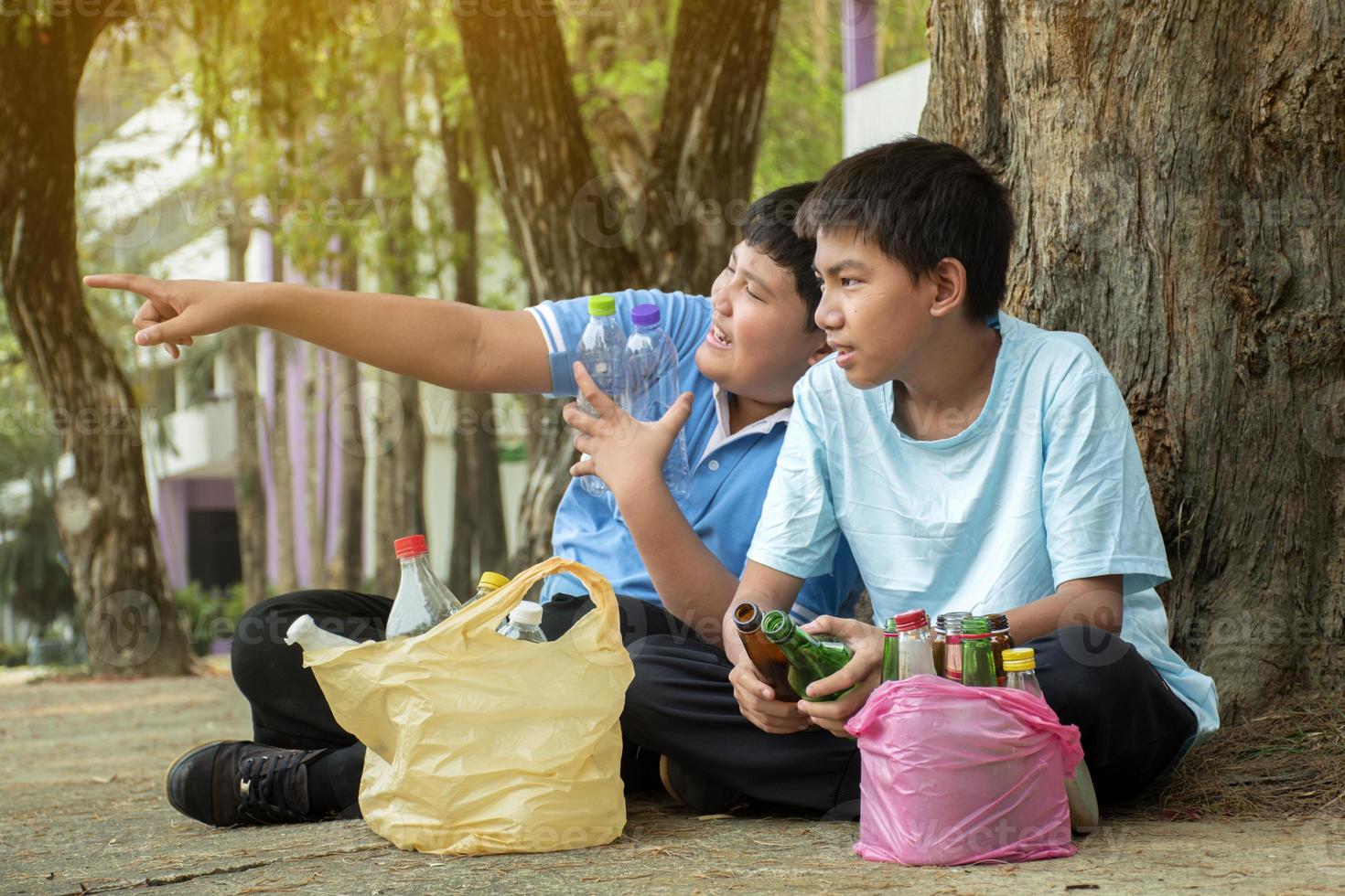 Young asian boy sorting various garbages and putting them into the boxes infront of him in the park, nature care and environment love concept. photo