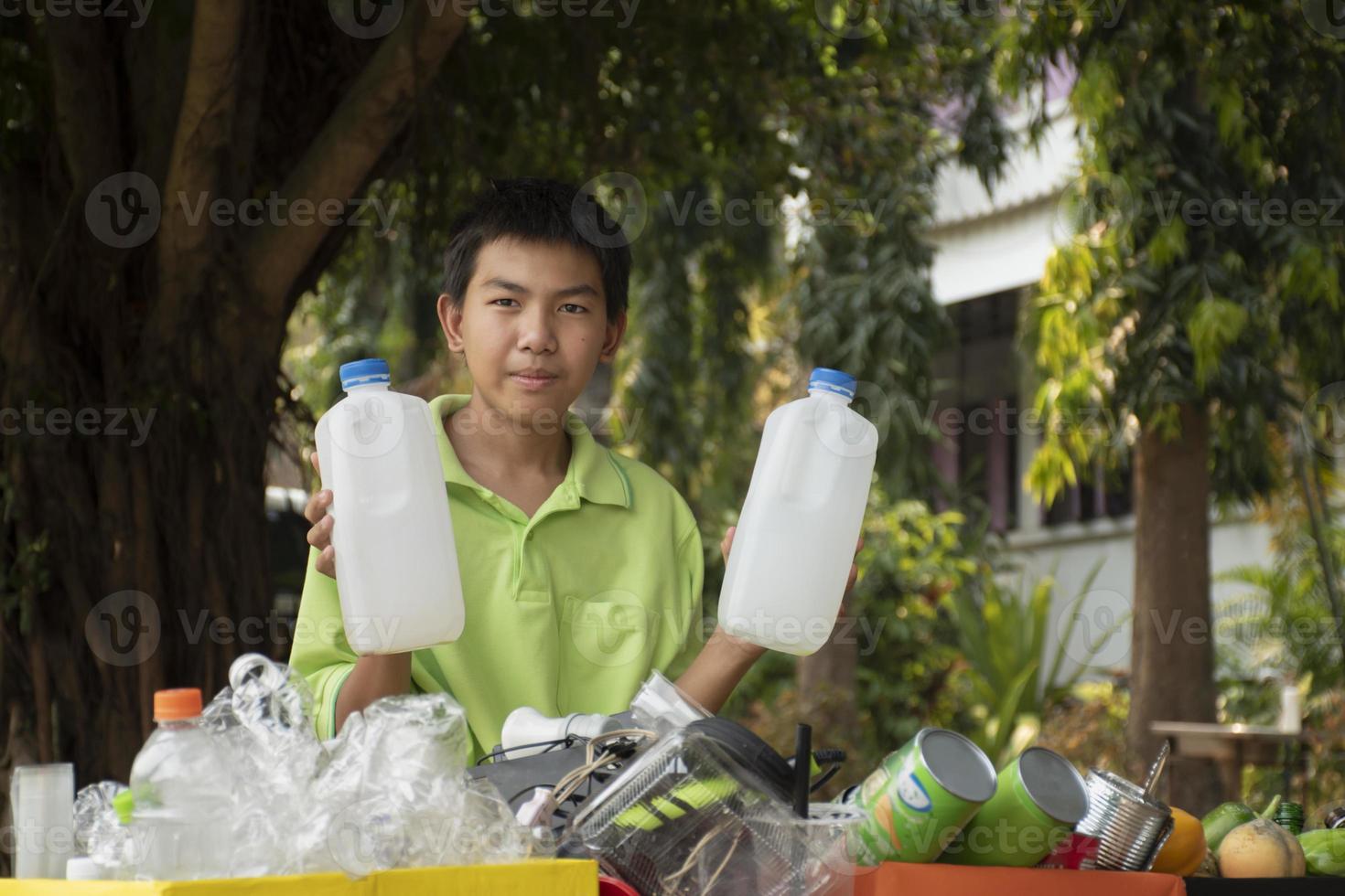 Young asian boy sorting various garbages and putting them into the boxes infront of him in the park, nature care and environment love concept. photo