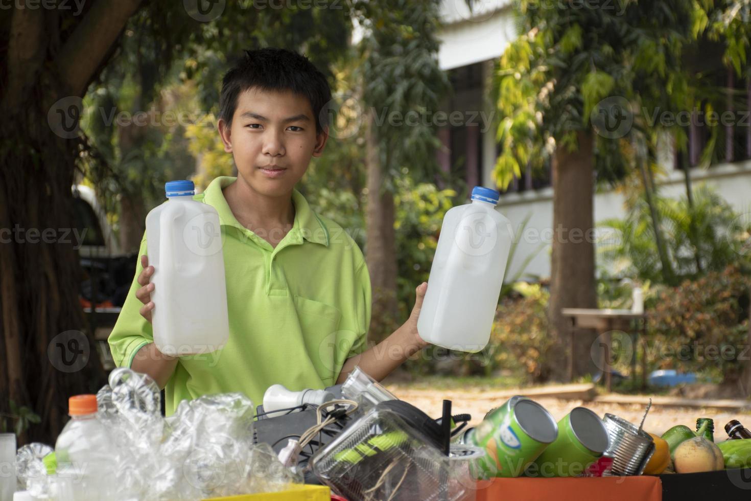 Young asian boy sorting various garbages and putting them into the boxes infront of him in the park, nature care and environment love concept. photo