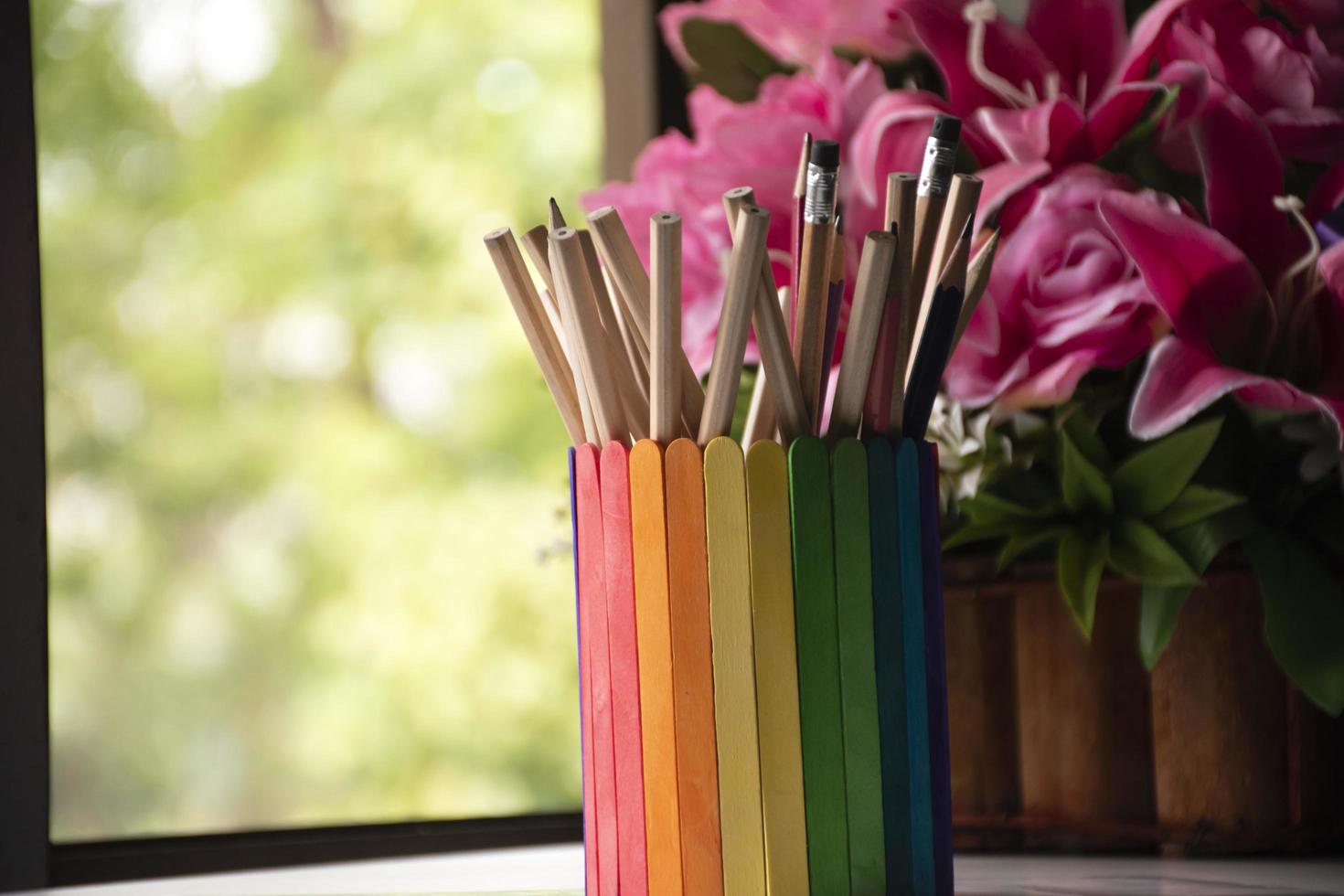 Closeup view of rainbow case which has various pencils inside, blurred nature ouside window background, concept for LGBT celebration in pride month and home decoration of LGBT people around the world. photo