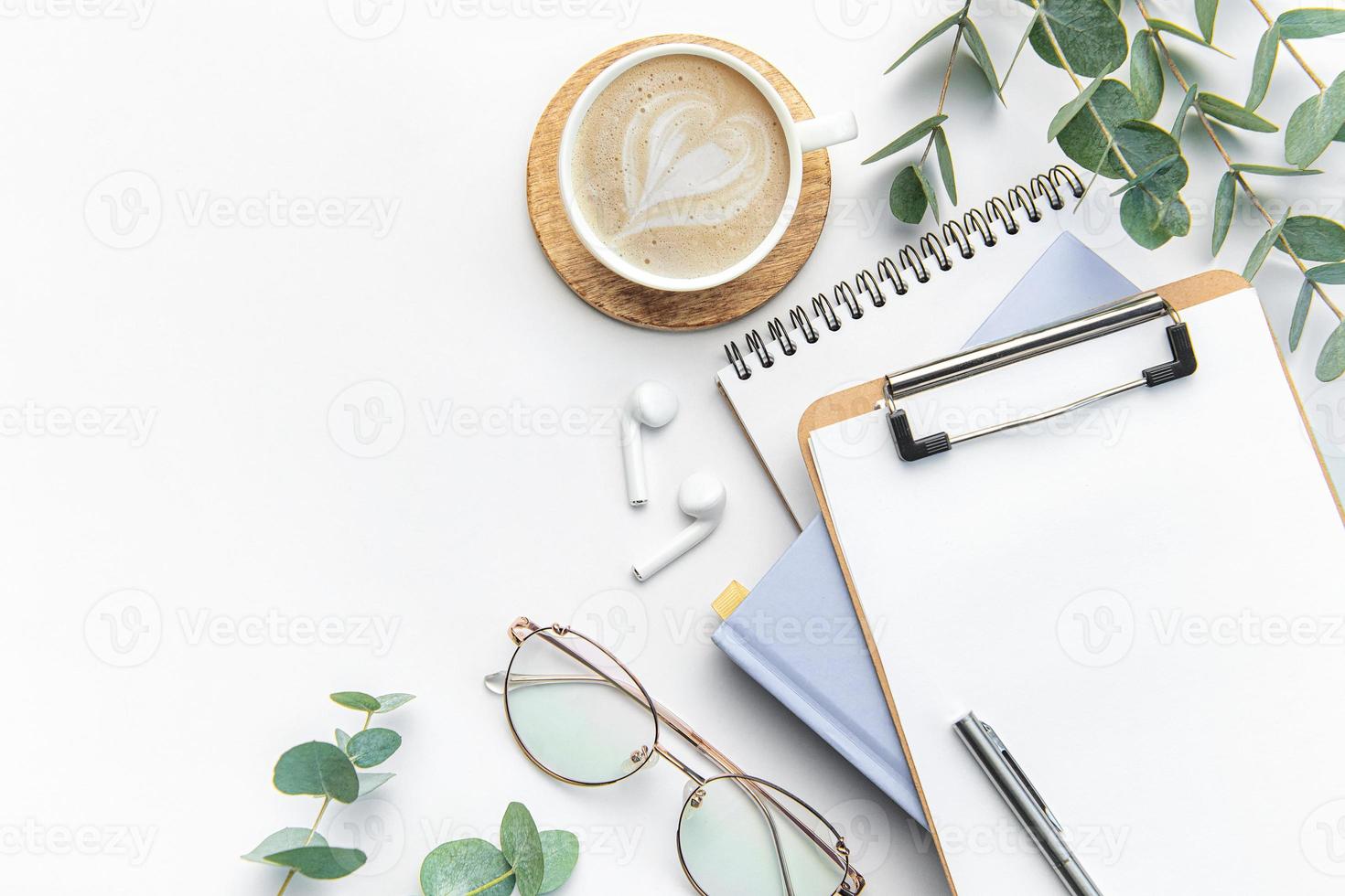 Modern white office desk table with coffee, notebook and other supplies. photo