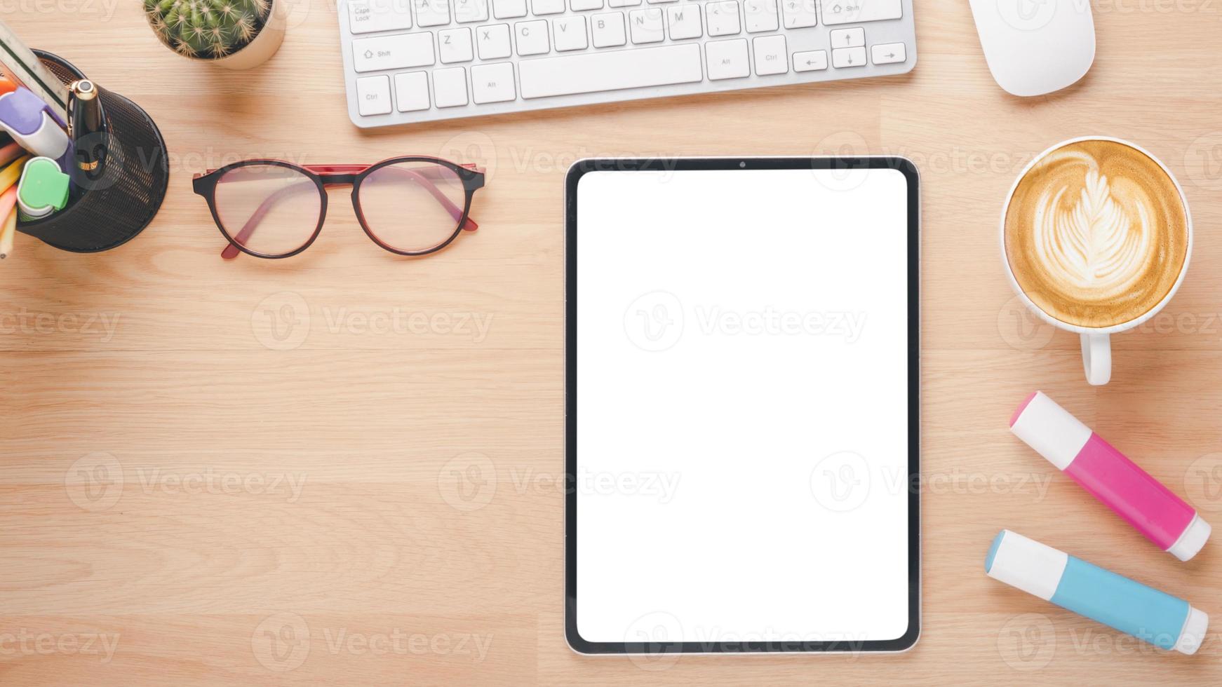 Wooden desk workplace with blank screen digital tablet, keyboard computer, mouse, eyeglass and cup of coffee, Top view flat lay with copy space. photo