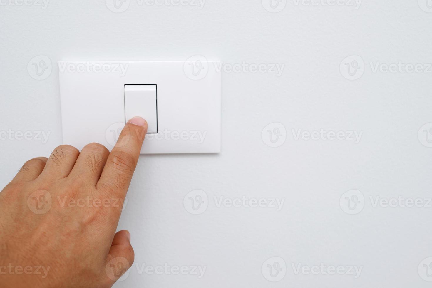 Turn off the light, close up finger man hand is closing the power switch with wall at home  to save energy. reduce global warming. photo