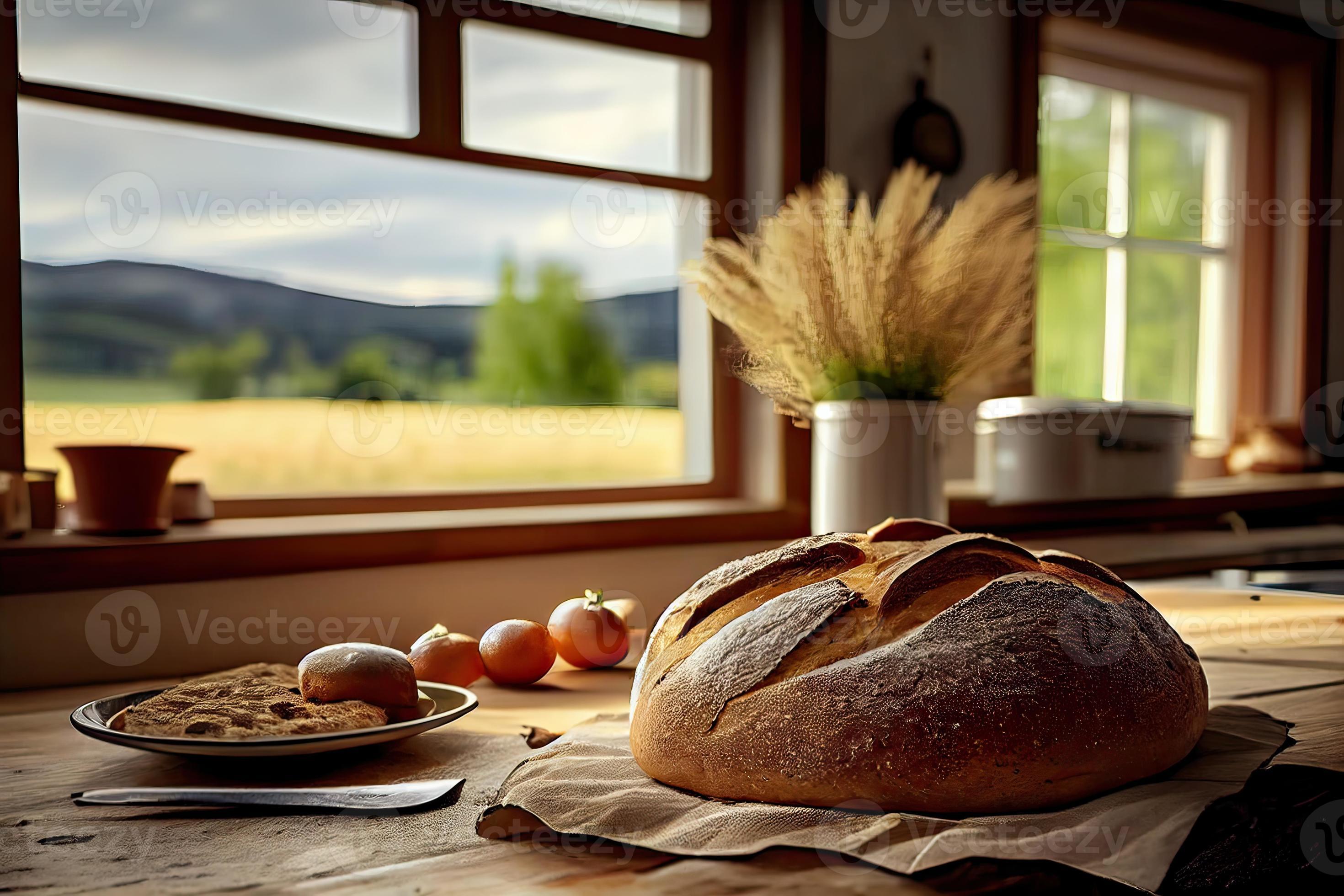 Fresh bread on the kitchen table in front of a window with a