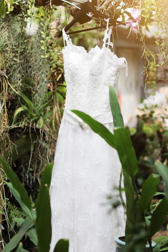 Bridal wedding dress hanging on the tree branch in the garden photo