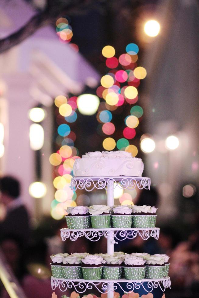 Wedding Cupcakes with colorful sprinkles in green cup with garland lights bokeh background photo