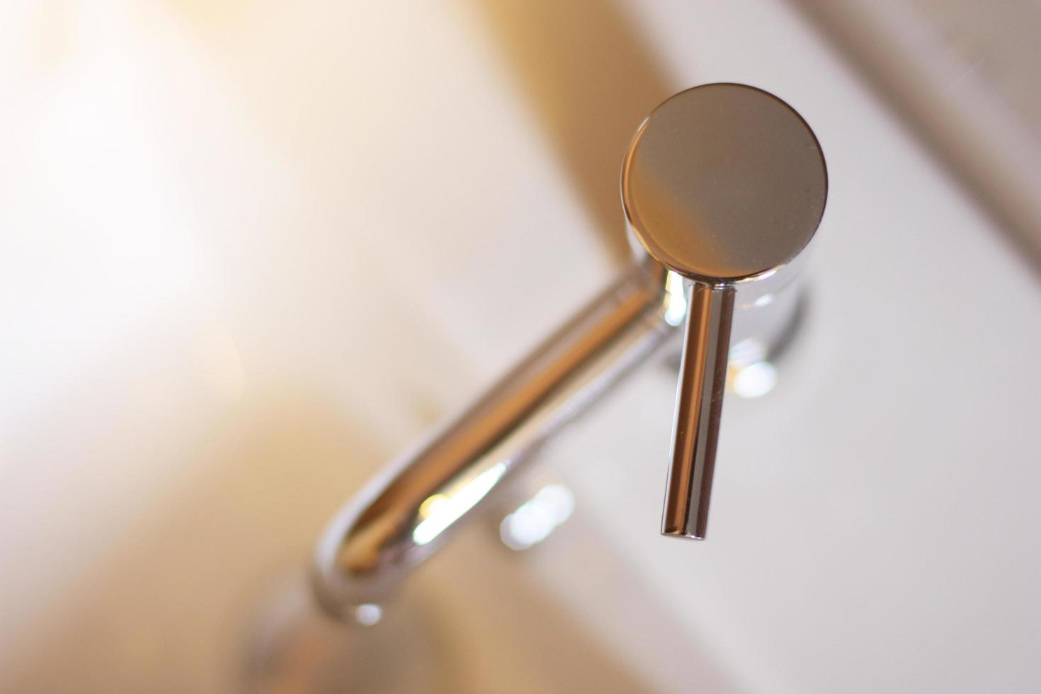 Closed up Silver Steel Basin Faucet with sunlight on top view in the bathroom. photo