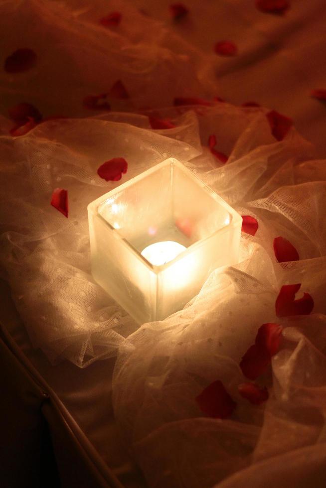 Candle light and red roses petals decoration on white cloth for wedding and valentine day photo