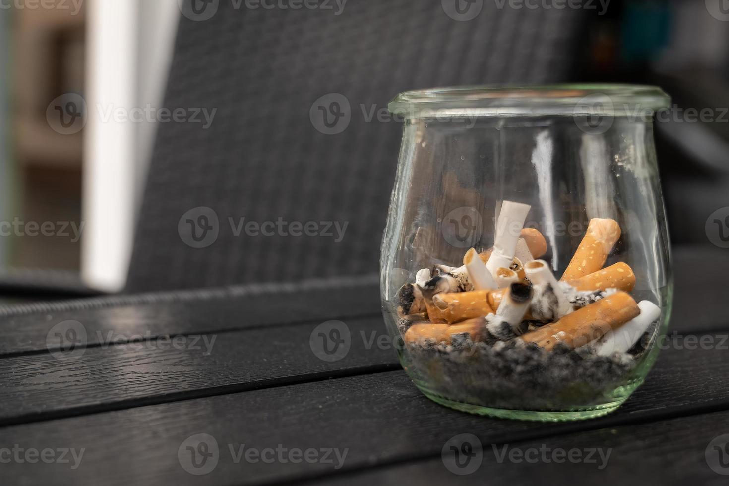 glass with old cigarettes on a table photo