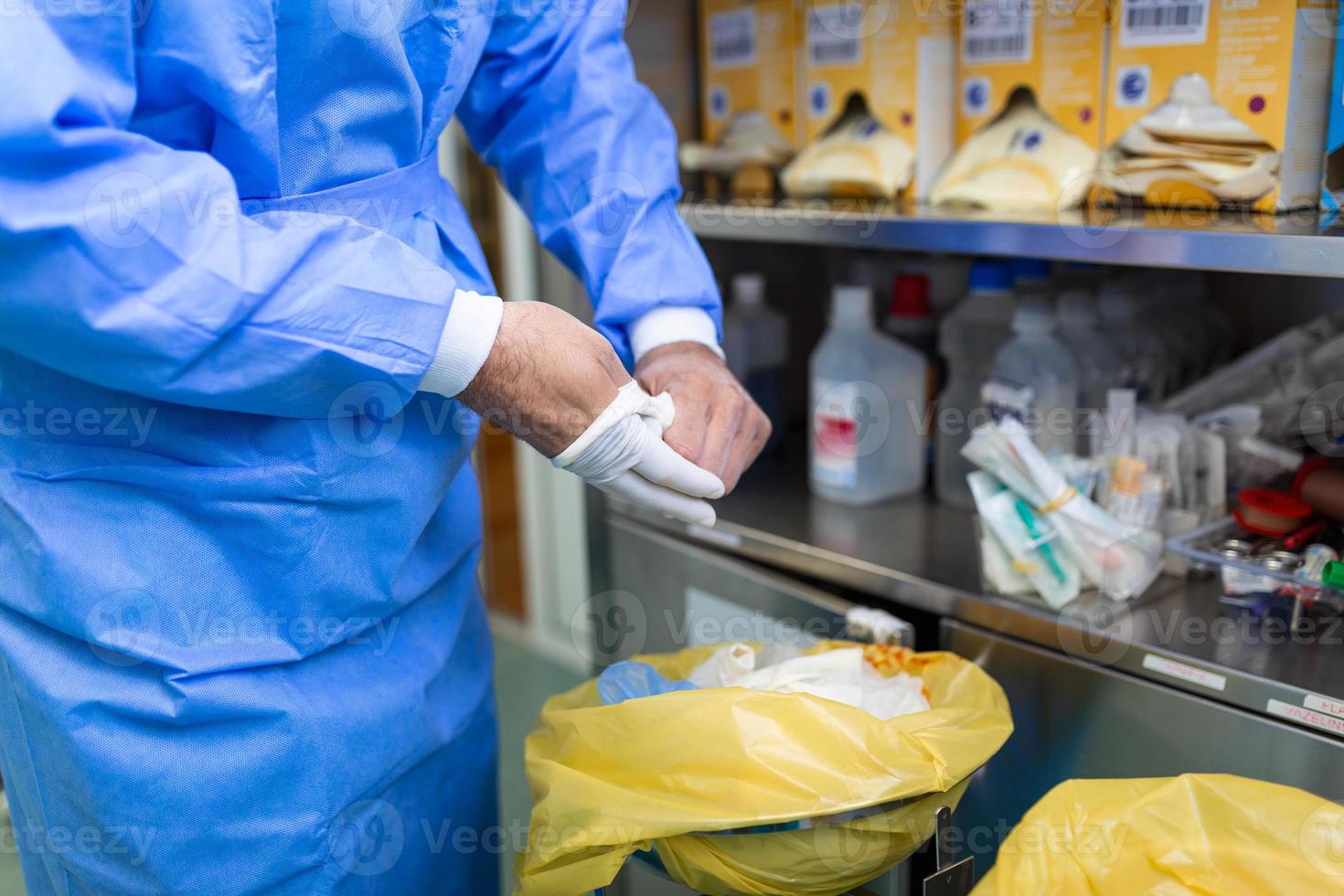 Male surgeon removing surgical gloves in operation theater at hospital photo