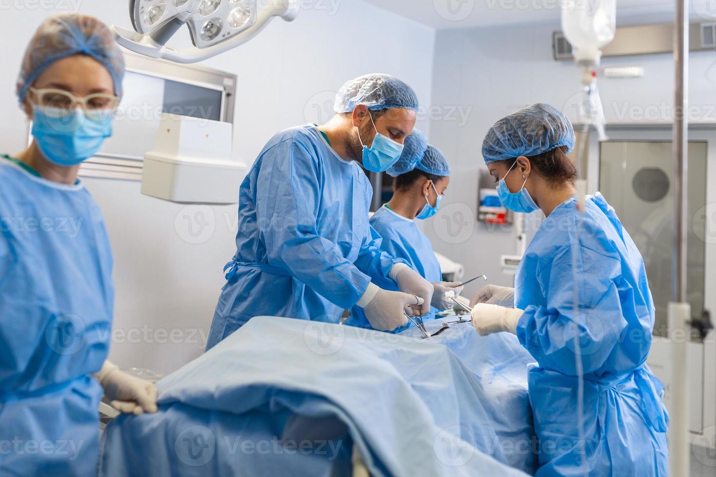 Surgical Team Working In Operating Theatre Wearing Protective Clothing photo