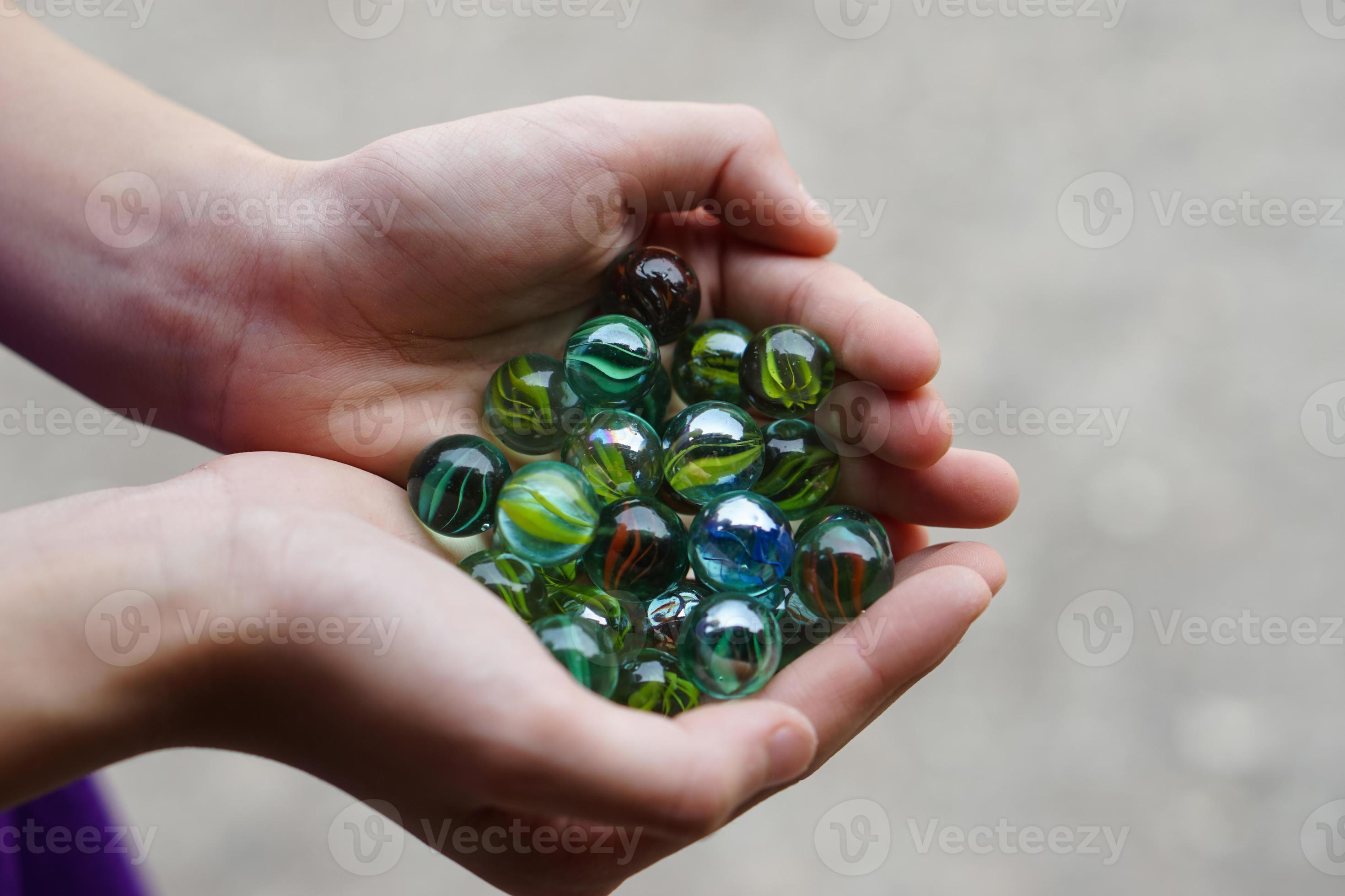 Close Up hands hold round small marble balls. Concept, Children's toy as bullets shoot by