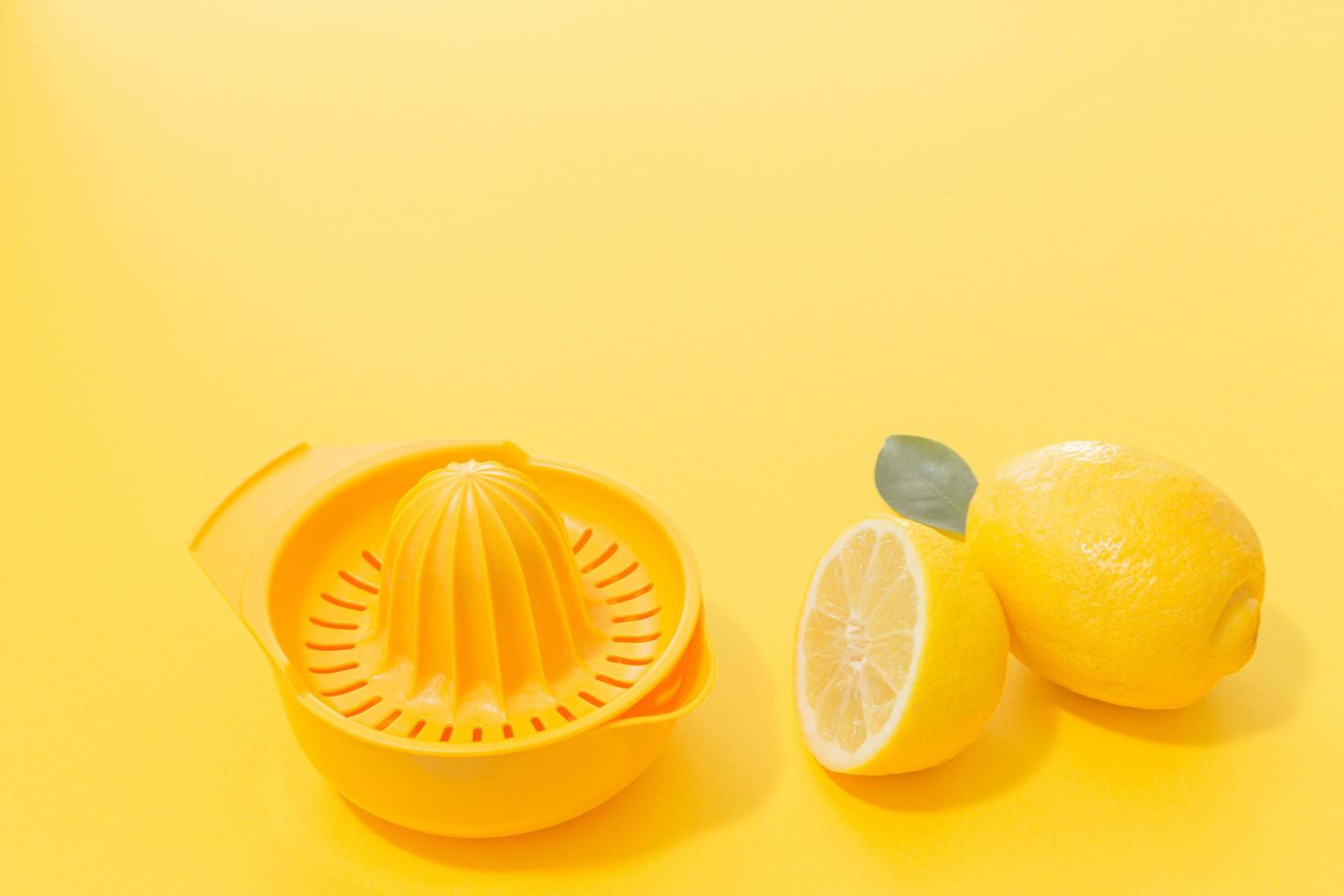 Lemons and yellow lemonade plastic strainer on yellow Background. Minimal concept. photo