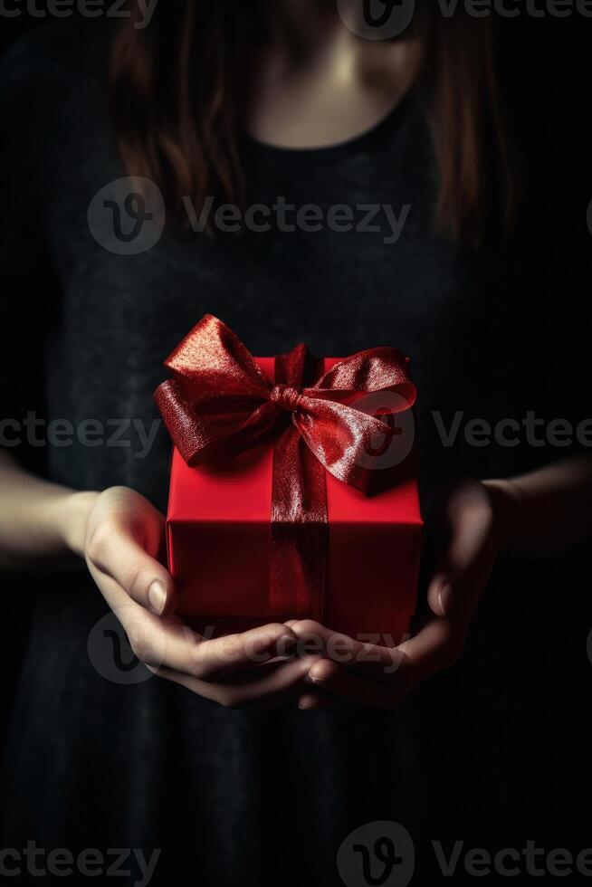 Gift box with red ribbon bow in female hands. photo