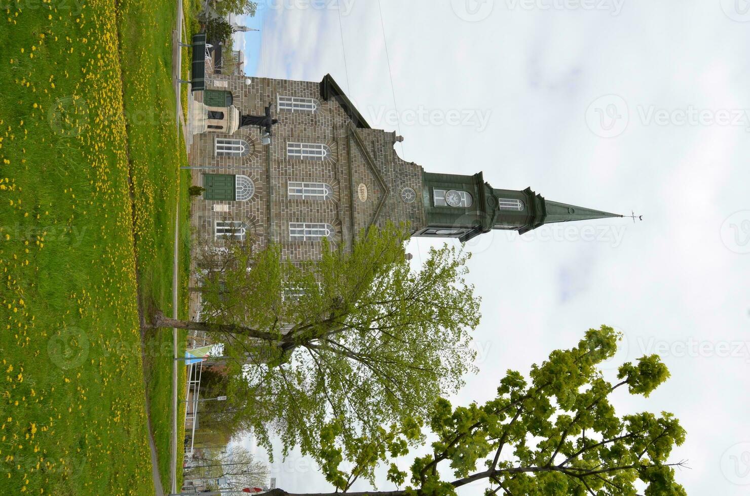 church building with green grass lawn with yellow dandelions photo