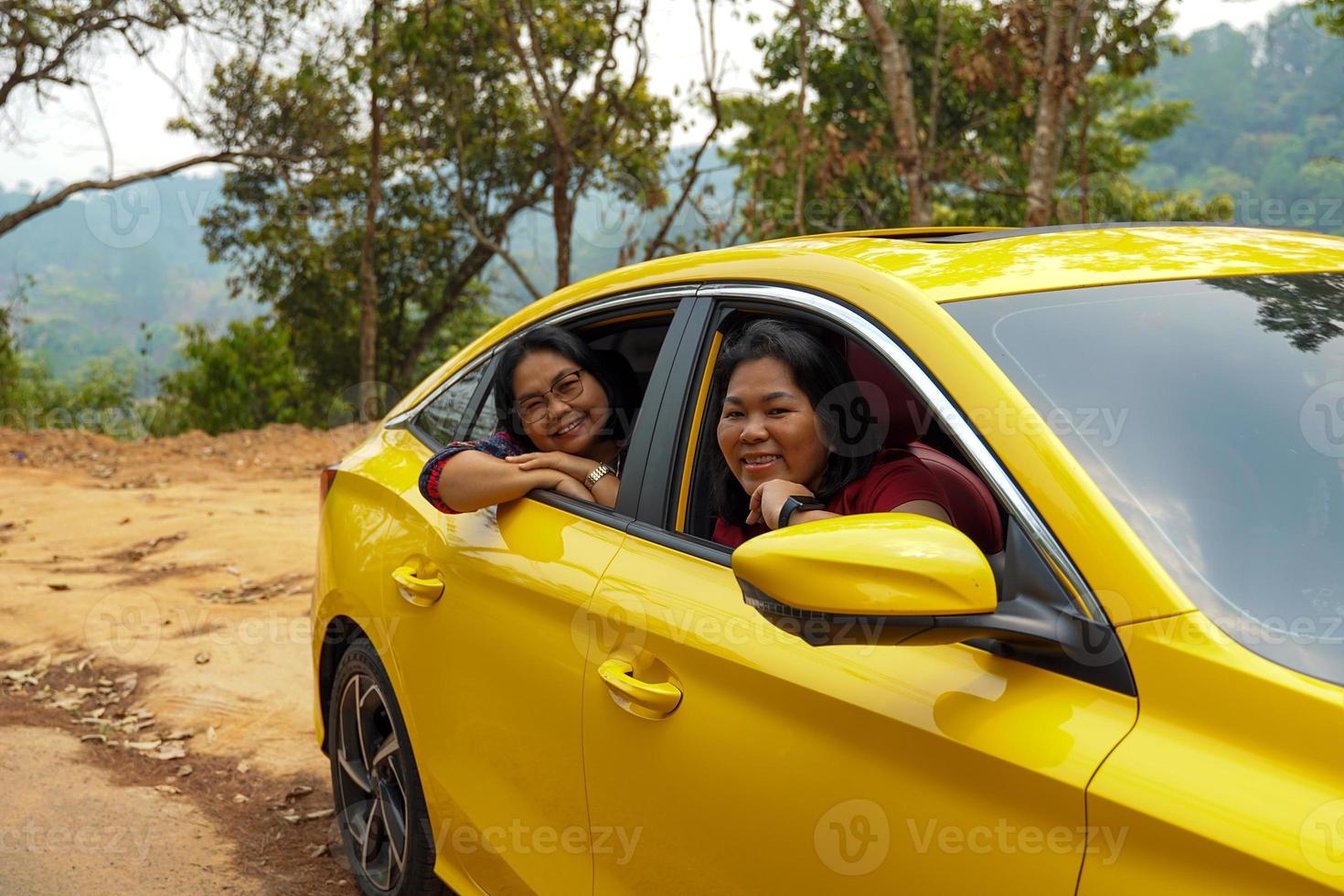 de edad mediana asiático mujer y amigo con un del amante amarillo sedán. todos sonrió felizmente. a viaje el montañas en un verano vacaciones juntos.suave y selectivo enfocar. foto