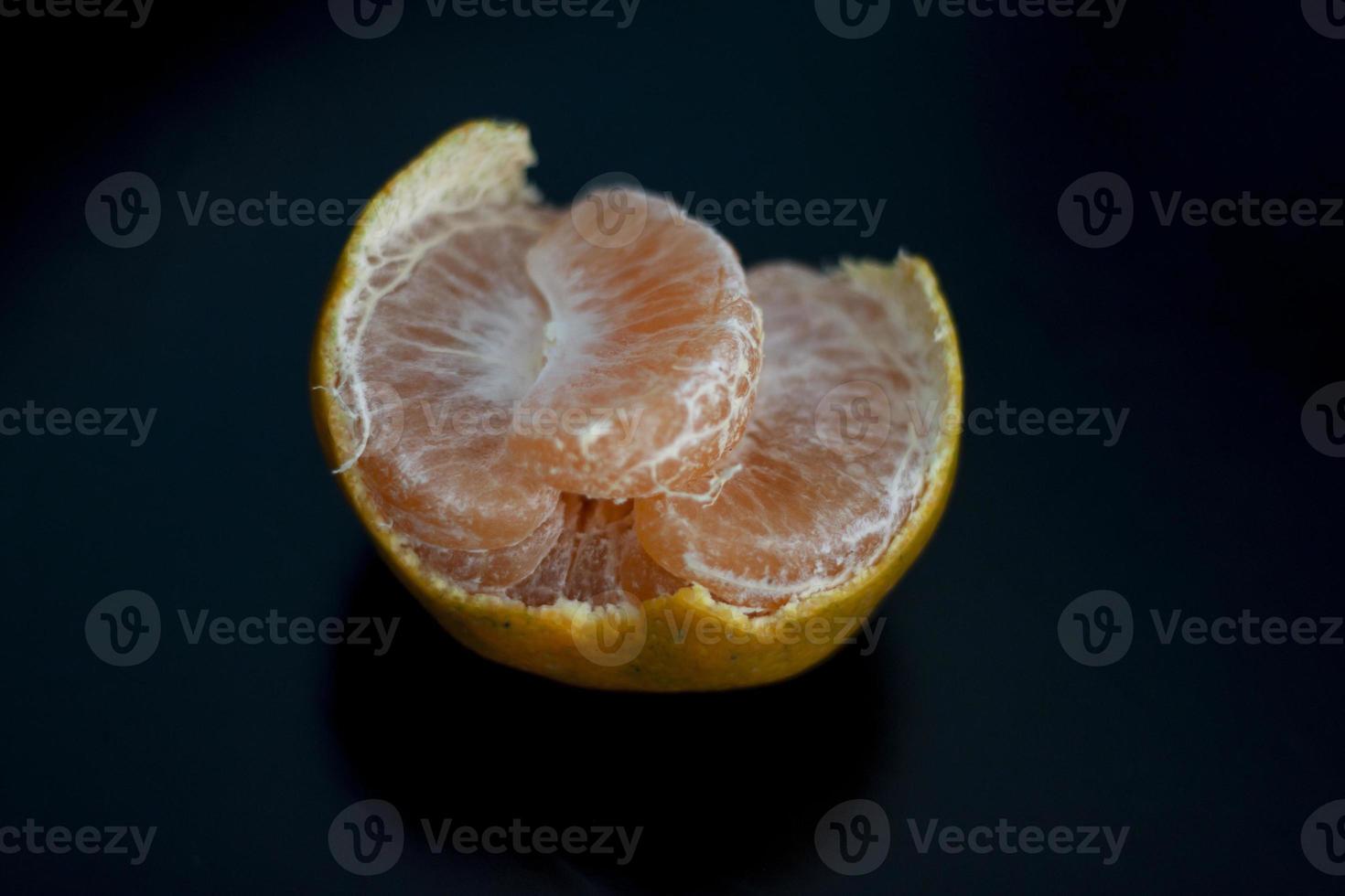 Mandarin orange and peeled segments isolated on black background. photo