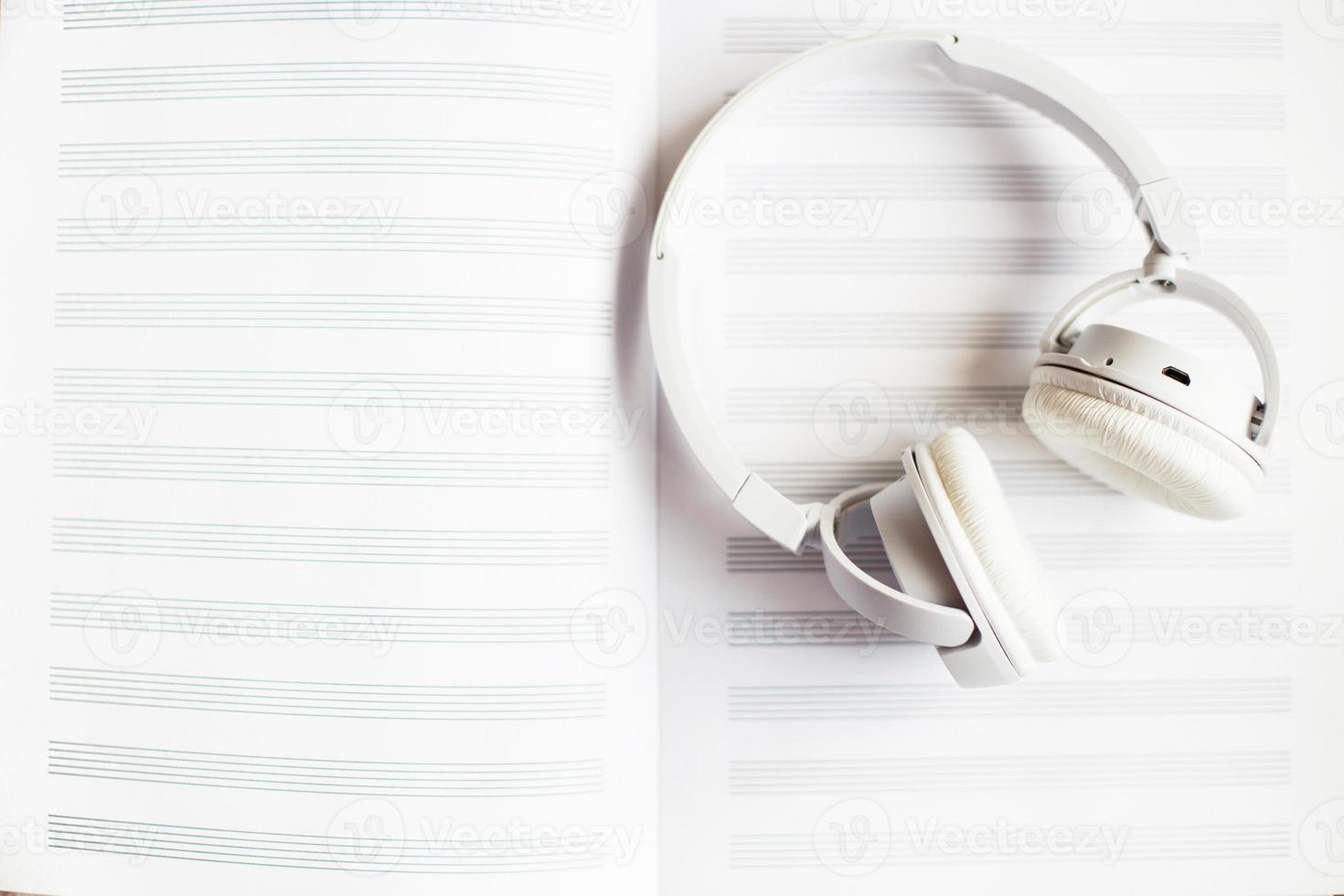 white headphones on a notebook for notes on a white background photo