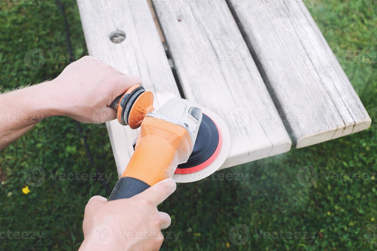 man polishes the board on the bench. man repairing bench in the garden photo