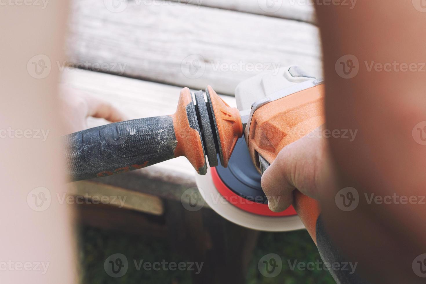 man polishes the board on the bench. man repairing bench in the garden photo