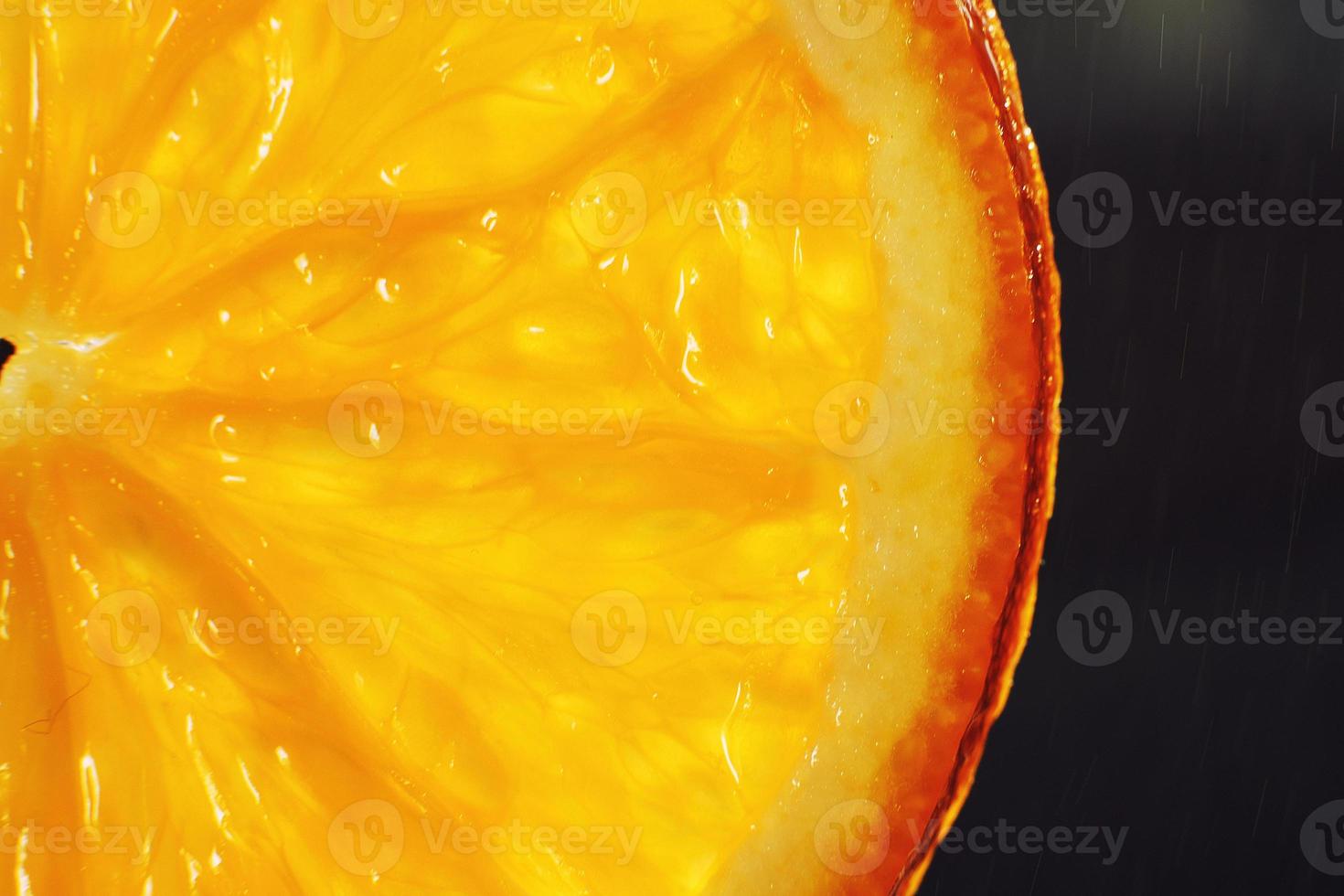 orange slice macro with a drop of water background . juicy orange sliced closeup on a dark background photo