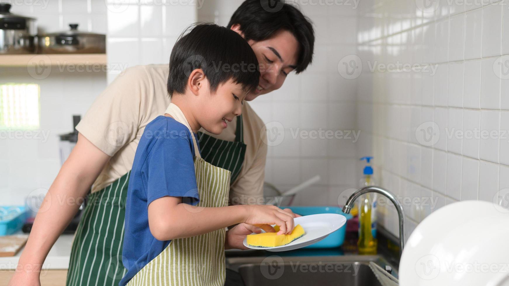 Happy smiling Young Asian father and son washing dishes in kitchen at home photo