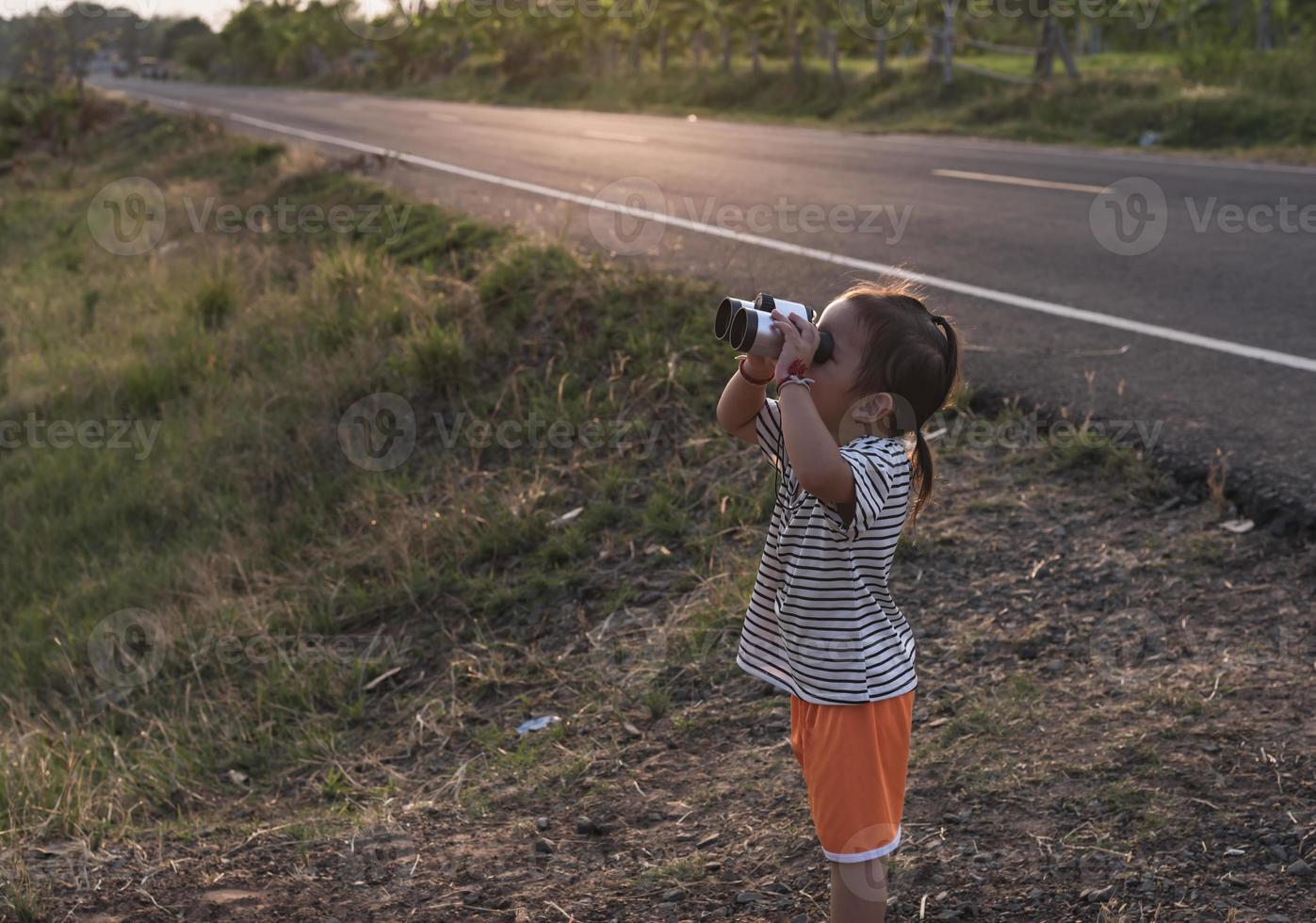 linda niña mirando mediante prismáticos, concepto de senderismo, cámping y aventura. foto