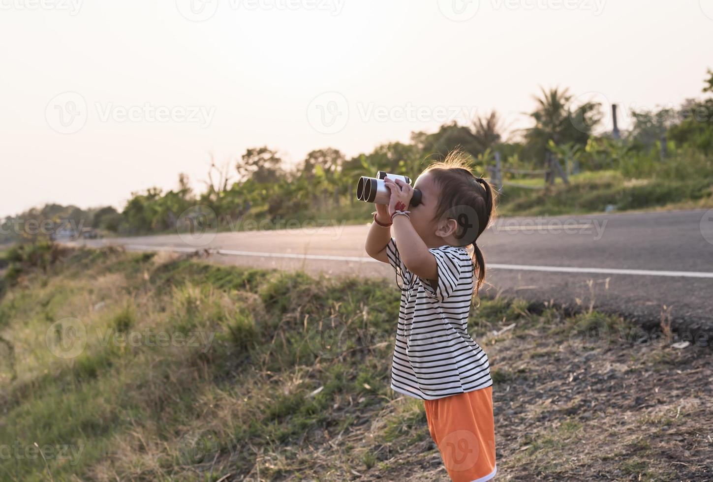 linda niña mirando mediante prismáticos, concepto de senderismo, cámping y aventura. foto