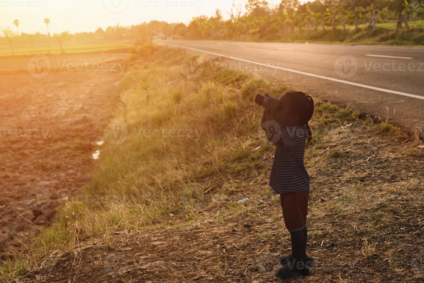 silhouette at sunset cute girl looking through binoculars Concept of hiking, camping and adventure. photo