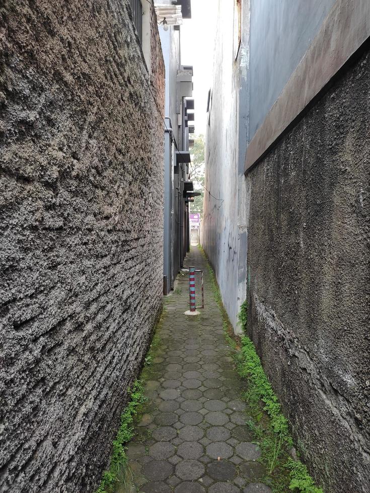 muy estrecho callejón con paredes de casas en ambos lados y con pavimentación bloques camino foto