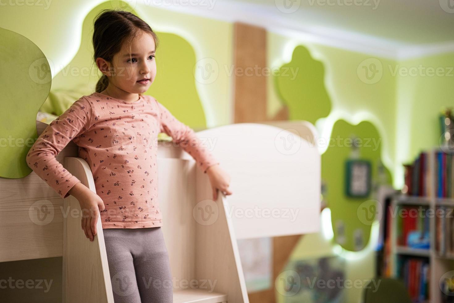 Young girl on bunk bed at her room. photo