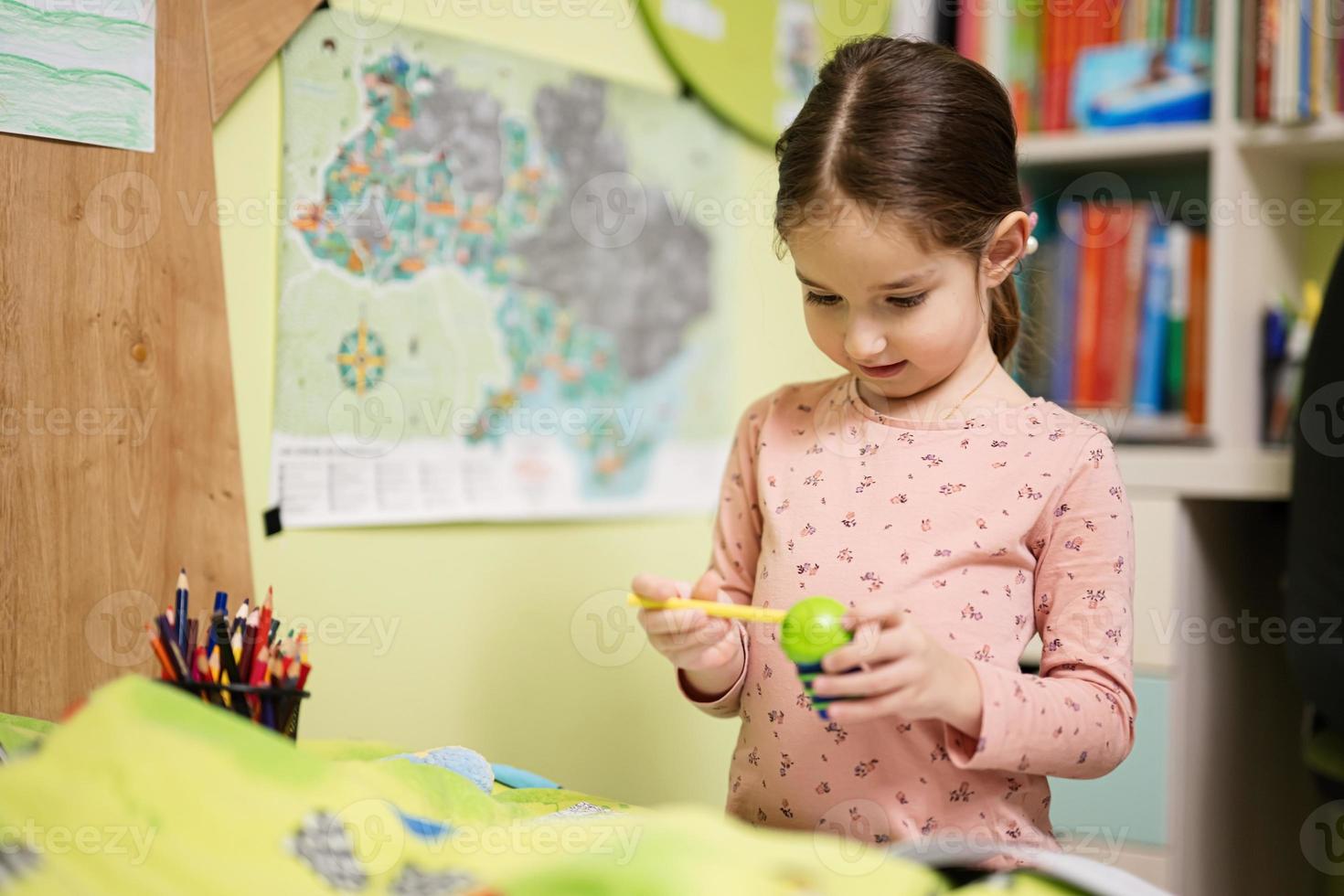 Young girl sharpening pencil in her room. photo