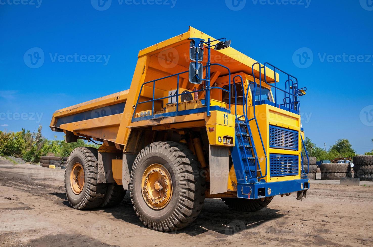Quarry yellow dump truck drives alone industrial area at sunny day photo