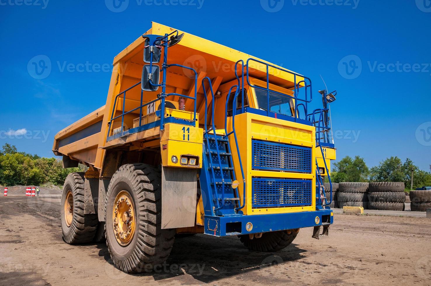 Quarry yellow dump truck drives alone industrial area at sunny day photo