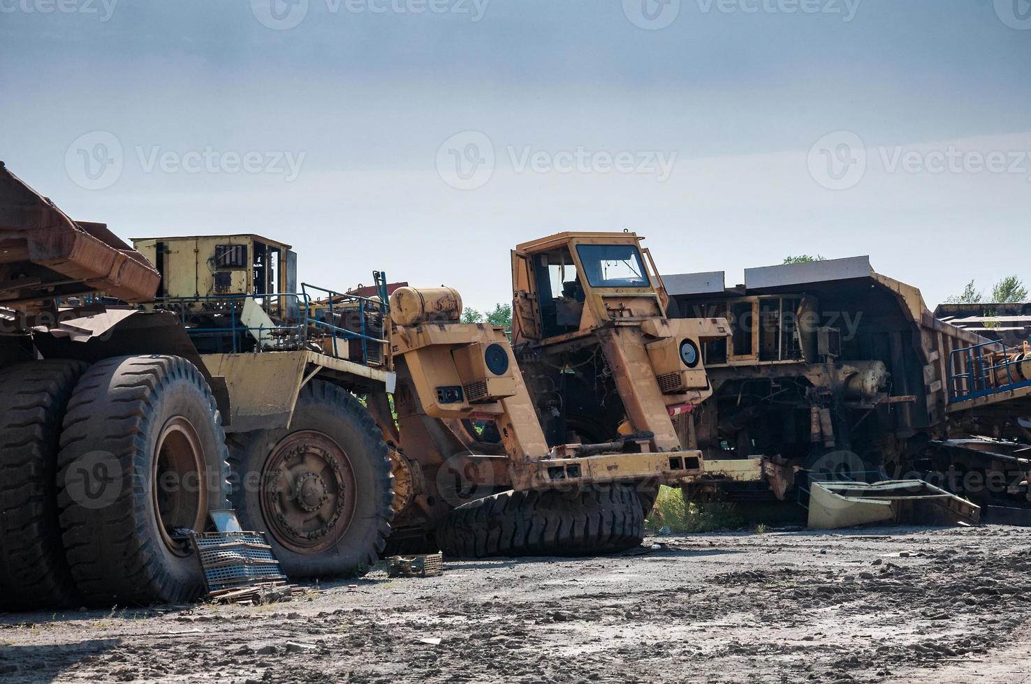 remains of old quarry trucks and machinery on junk yard at sunny day photo