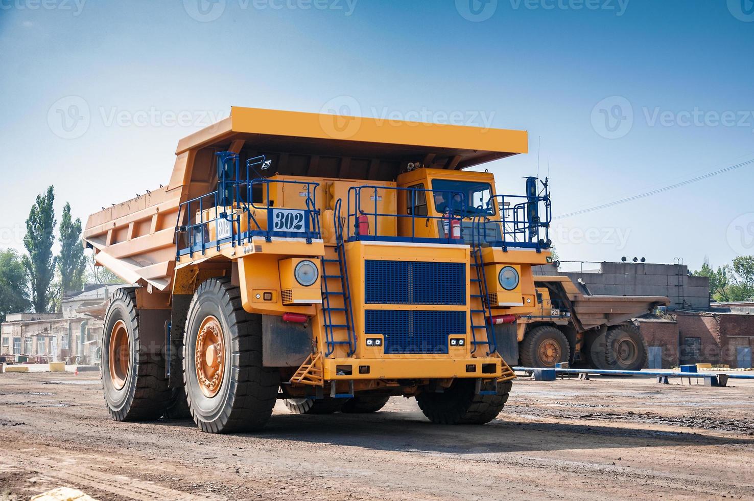 Quarry yellow dump truck drives alone industrial area at sunny day photo