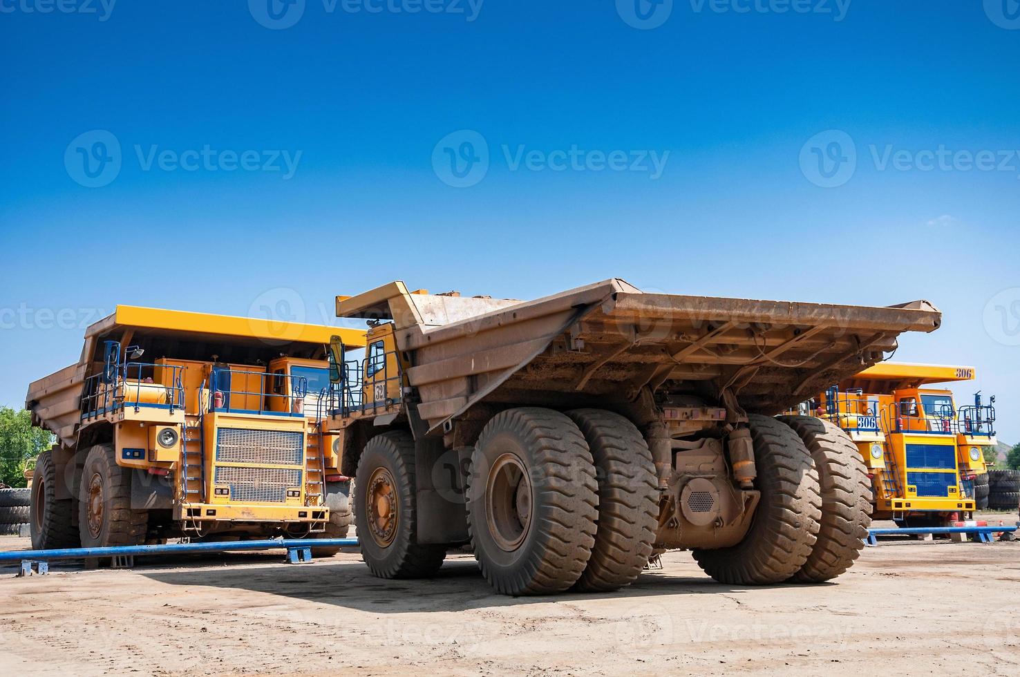 heavy yellow open cast mine dump trucks at repair station at sunny cloudless day photo